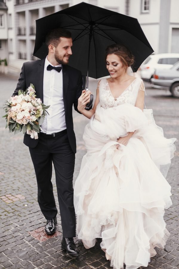 gorgeous-bride-and-stylish-groom-walking-under-umbrella-in-rainy-street-and-smiling.jpg Gold Wedding Package